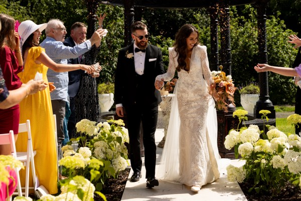 bride and groom exit ceremony as they walk down the aisle passing clapping guests