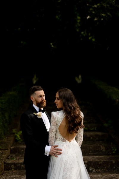 bride shows off back of dress as she stands beside groom