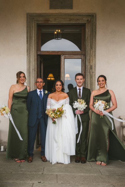 bride in the middle of groomsmen bridesmaids outside venue