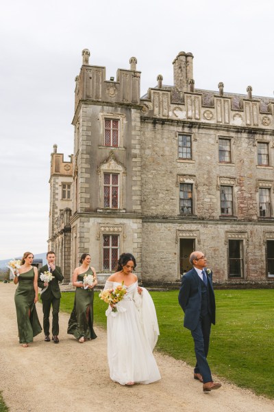 exterior wedding venue bride and bridesmaids on pathway with groom