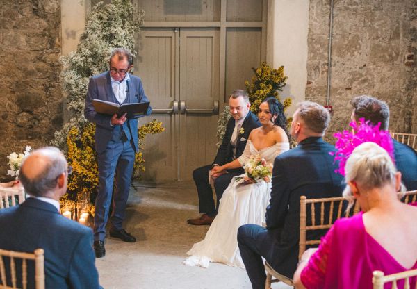 bride and groom sitting at alter celebrant reading speech