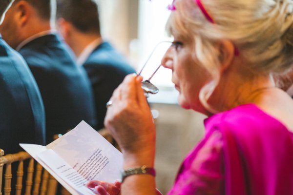 woman in pink outside dress reads pamphlet booklet