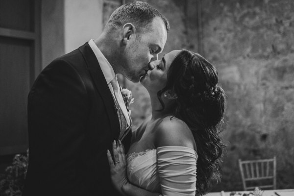 black and white of bride and groom kissing