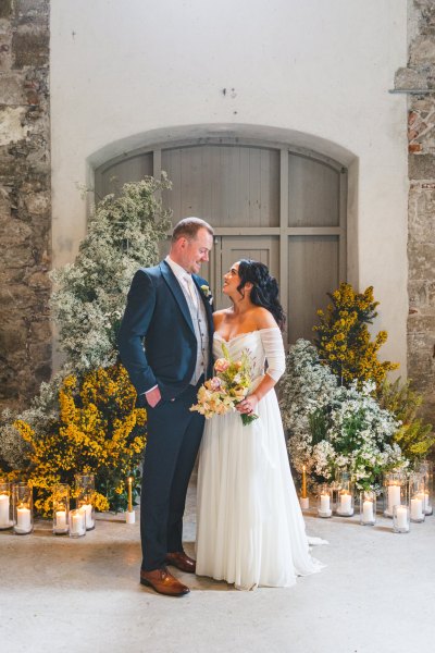 entrance door flowers surrounding and candles and bride and groom in shot facing each other