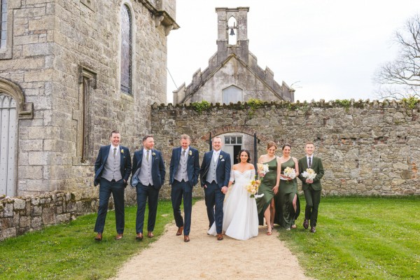 bride groom bridesmaids and groomsmen walk the pathway to wedding venue