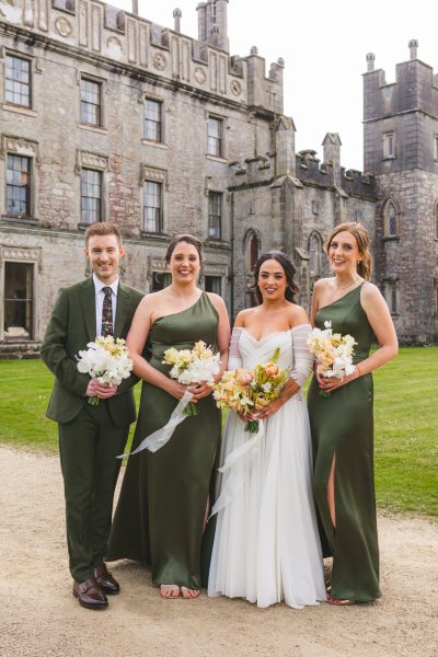 bride in the middle and bridesmaids on either side and brother smiling