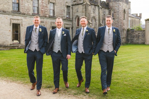 groom and groomsmen walk on the green grass