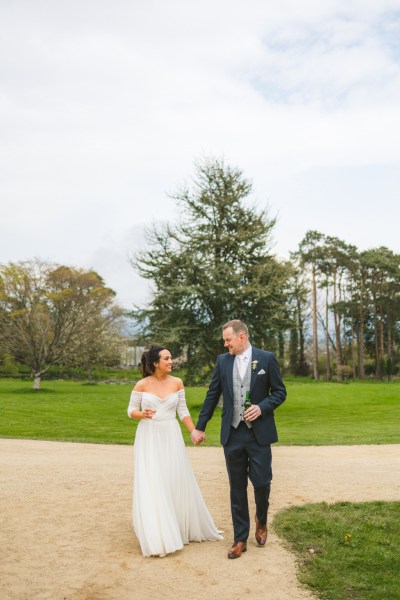 bride and groom walk the pathway to venue they are holding hands