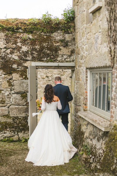 bride and groom from behind walk through the garden together