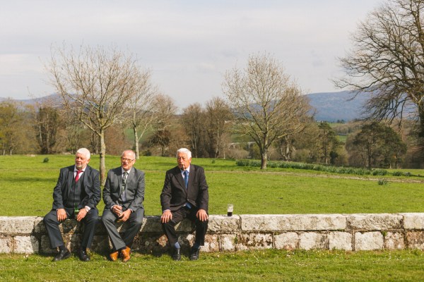 guests seated outside on bricked wall on grass