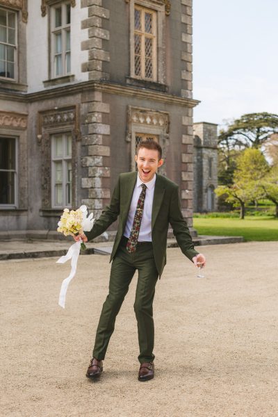 groomsman messing around in courtyard holding bouquet flowers