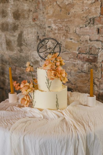 white wedding cake covered in autumnal flowers orange