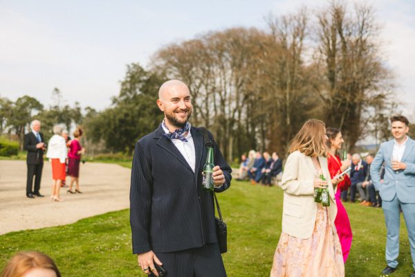 man standing on the grass enjoying bottle of beer