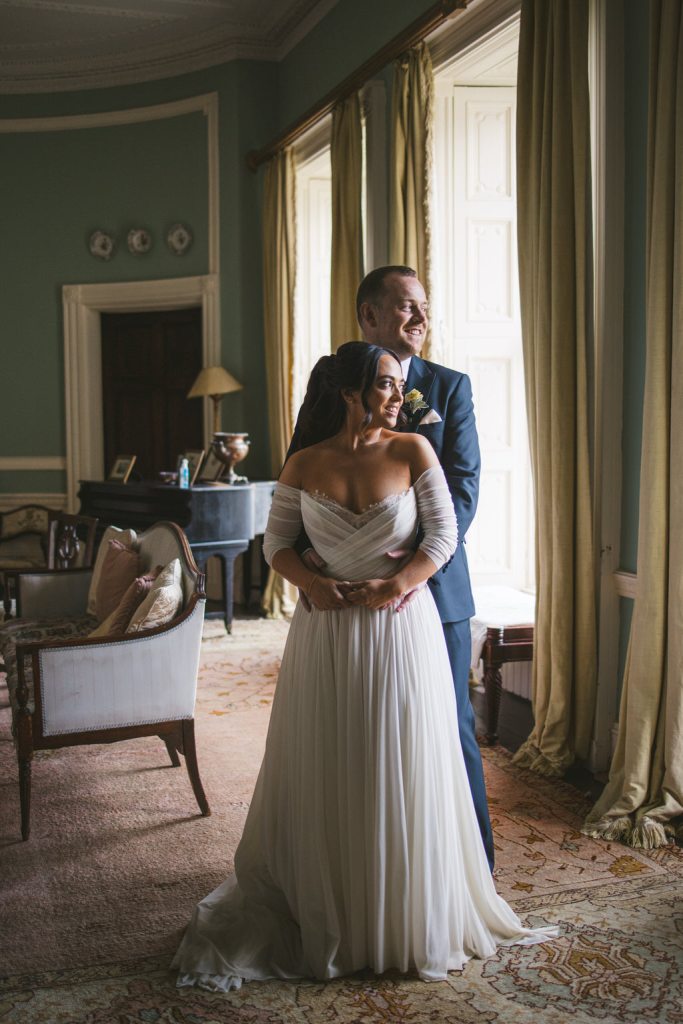 bride and groom look to their left out of window in room