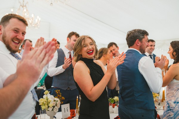 woman wearing black dress claps in audience