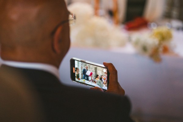 man in suit takes picture on phone or video