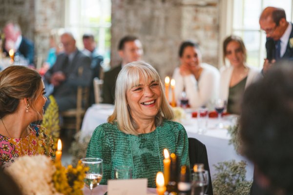 woman wearing green dress smiles at table candles lit