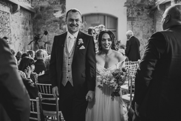 black and white shot of bride and groom exiting the wedding ceremony