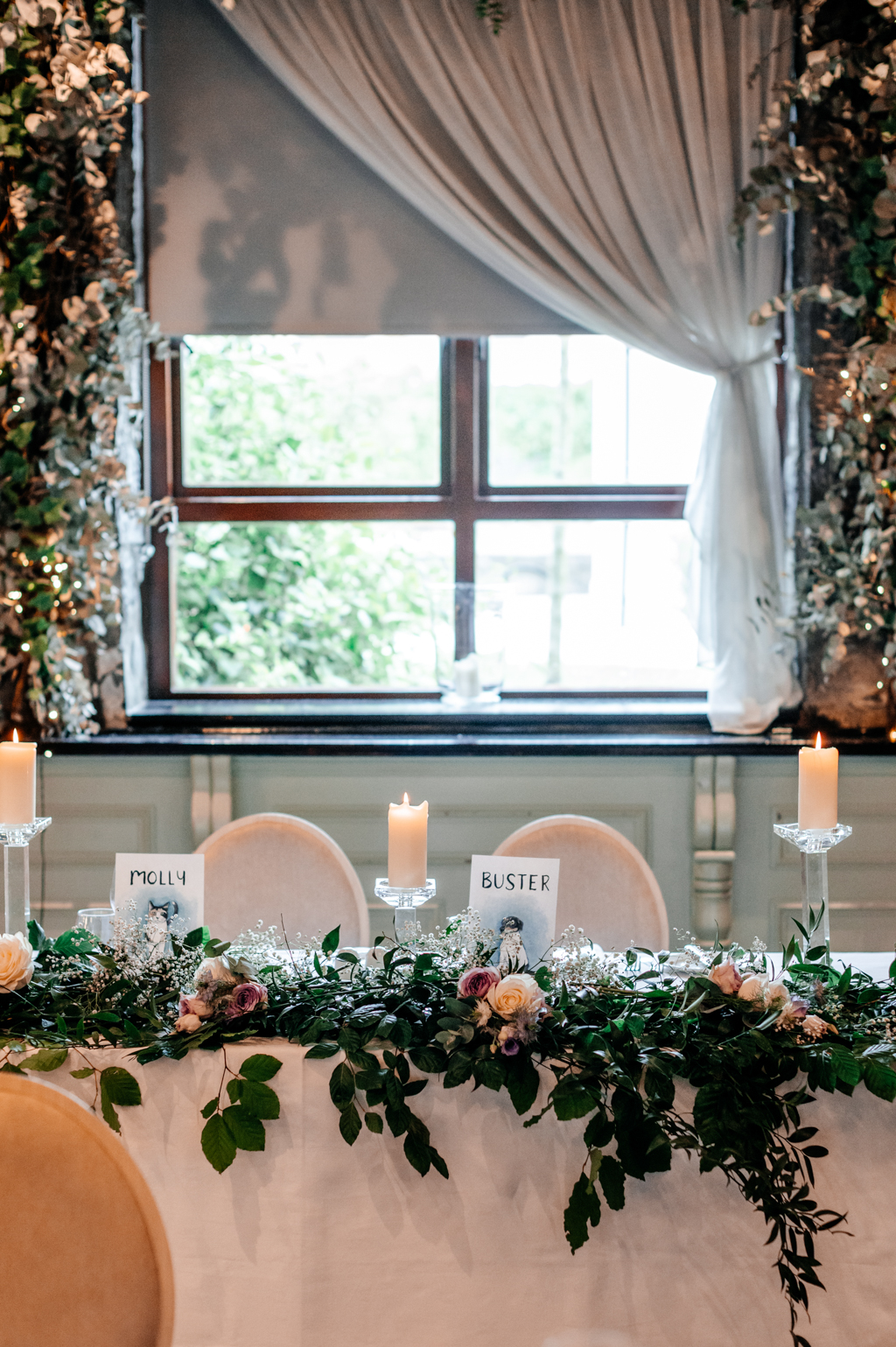 table setting for bride and groom candles lit window in background