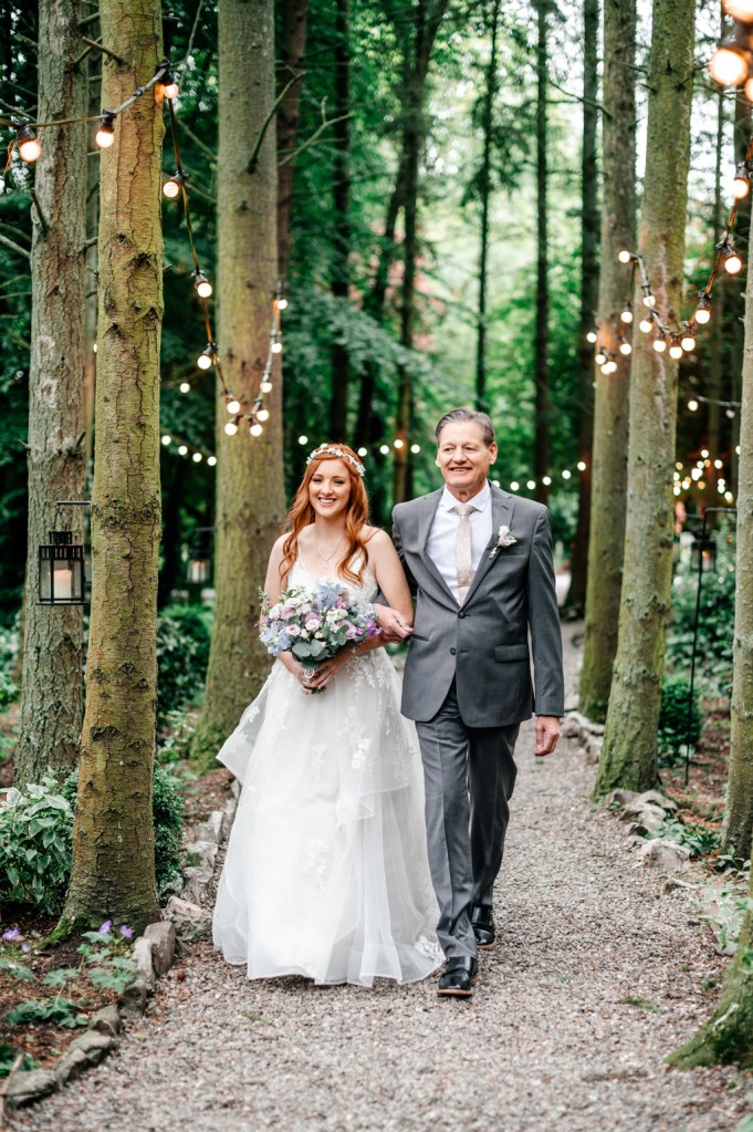 father of the bride walks his daughter down the aisle towards wedding