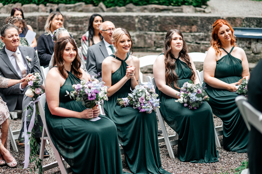 bridesmaids wearing green dresses clap in the audience