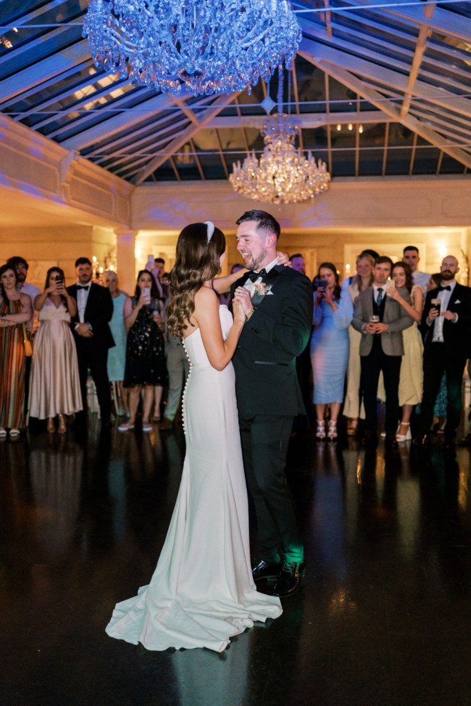 Bride and groom dance on a dancefloor as guests watch on