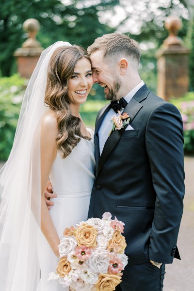 Bride and groom stand outside in front of a gate