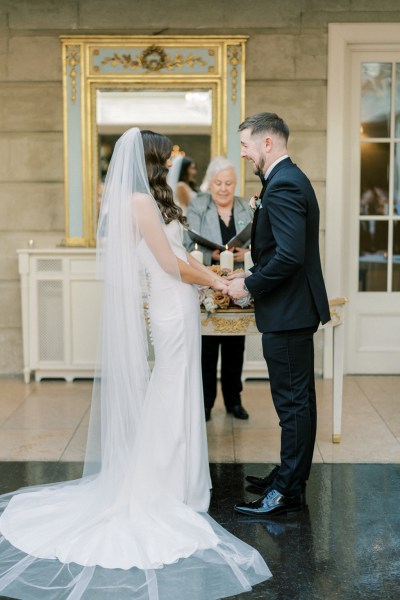 Bride and groom hold hands at top of alter in front of celebrant