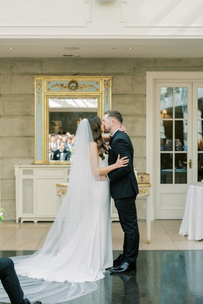 Bride and groom kiss at the top of the aisle