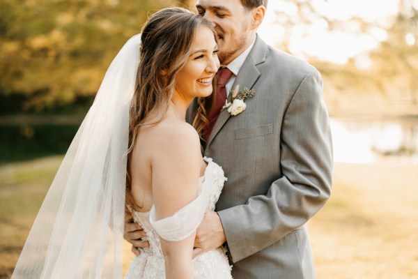 groom kisses bride on forehead as they pose in garden