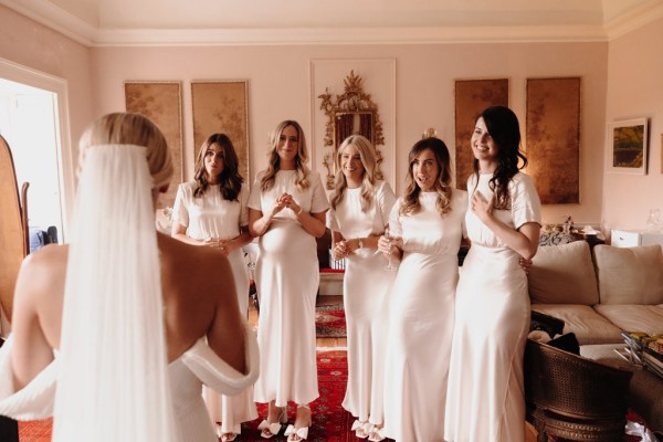 bridesmaids and bride in white they react all smiling roses bouquet