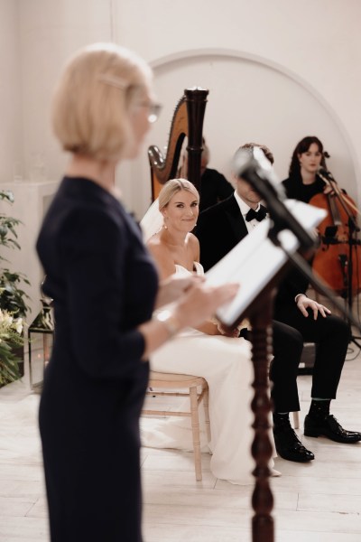 celebrant reads sermon into microphone bride groom seated at alter