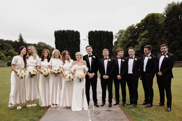 bride groom groomsmen bridesmaids all in a line in garden