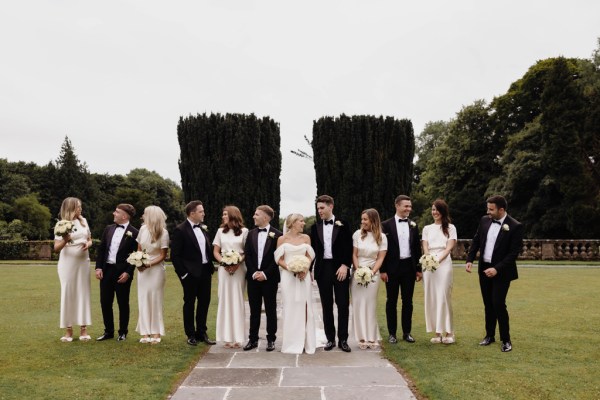 bride groom groomsmen bridesmaids all walking in a line in garden