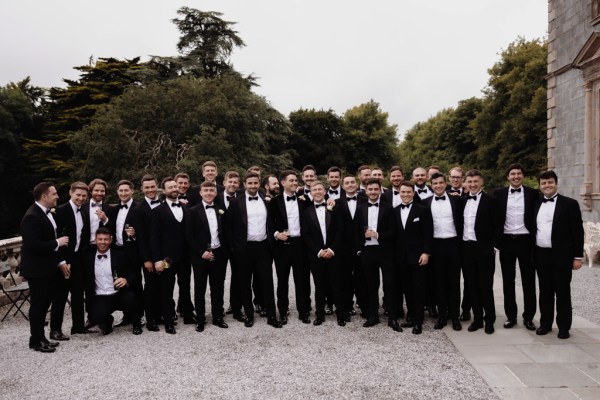 portrait of groom groomsmen men wearing black tuxedo suits in courtyard