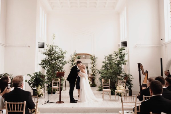 bride and groom kiss at the alter