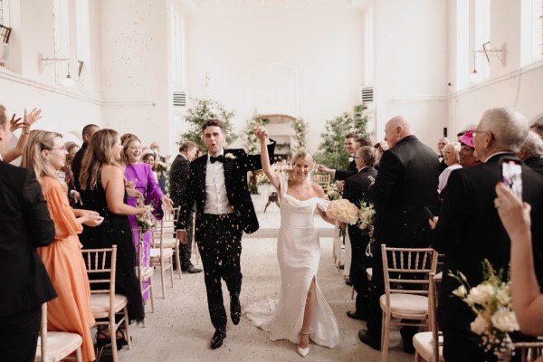 bride and groom exit ceremony hands in the air guests clapping