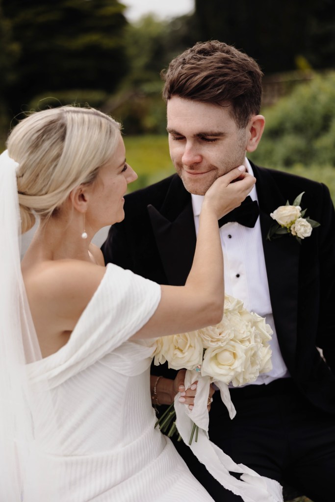 bride cups grooms face they smile at each other