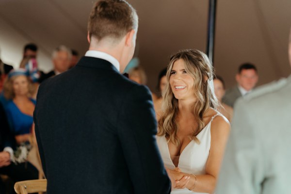 bride and groom stand and smile at each other at alter vows