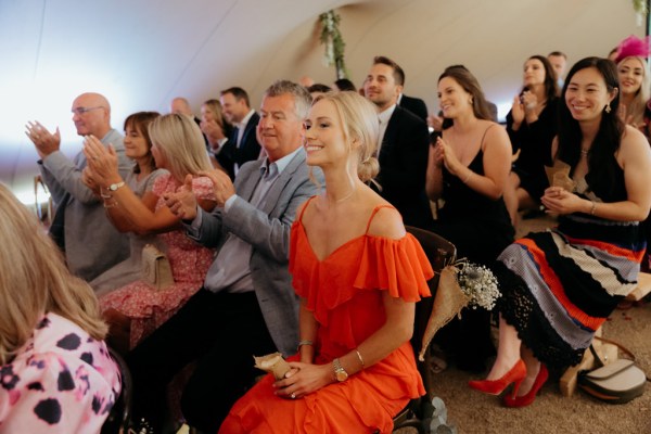 woman in red/blood orange dress seated during ceremony