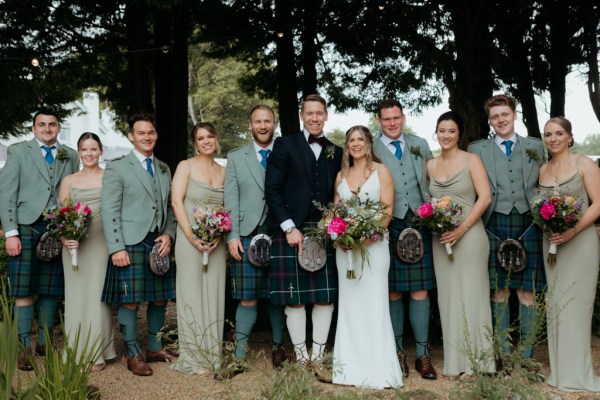 portrait of bride groom groomsmen and bridesmaids outside in park garden setting