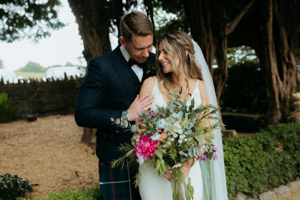 bride looks at groom over the shoulder in garden setting