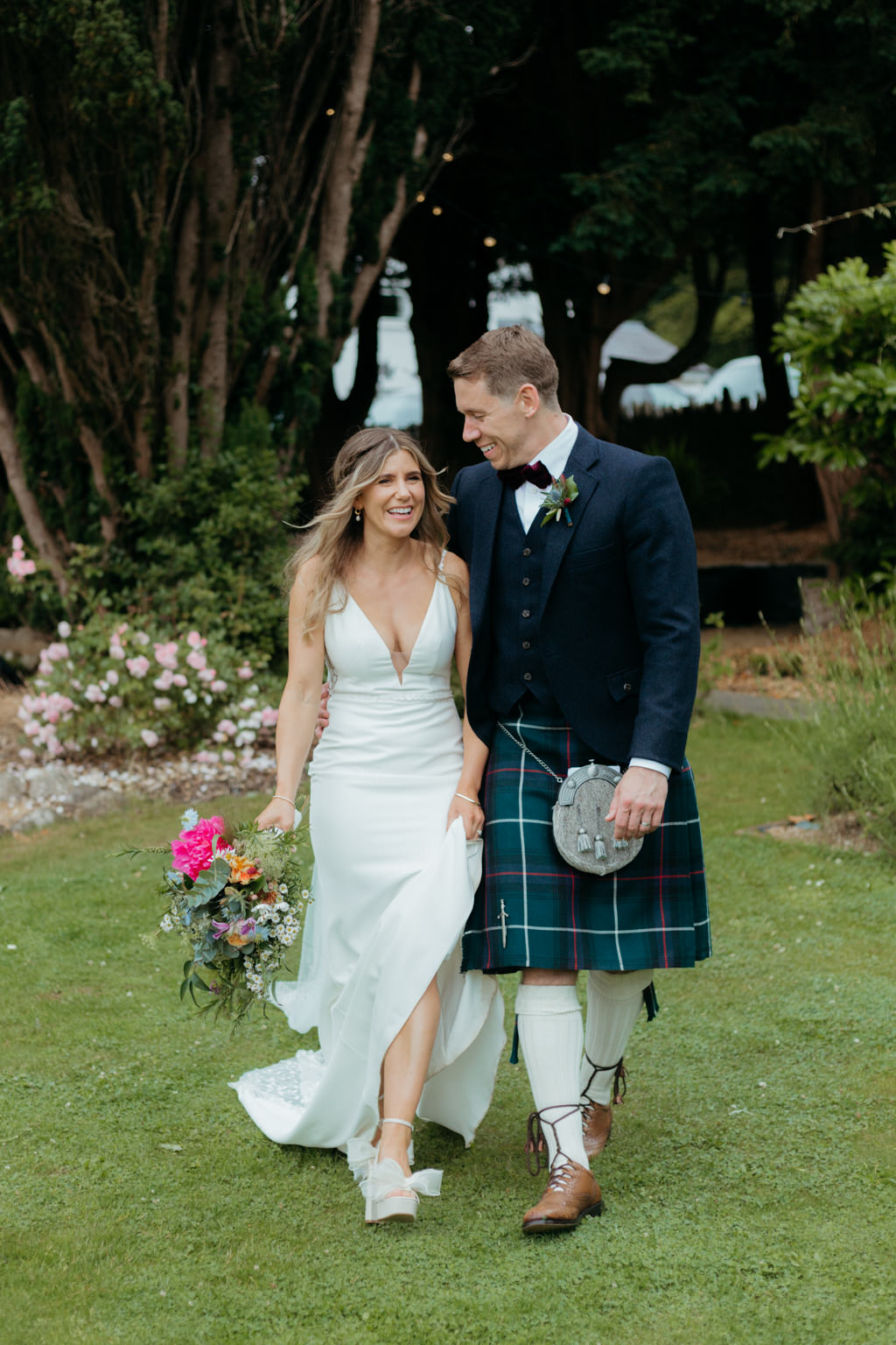 bride and groom walk on pathway to garden walking towards camera