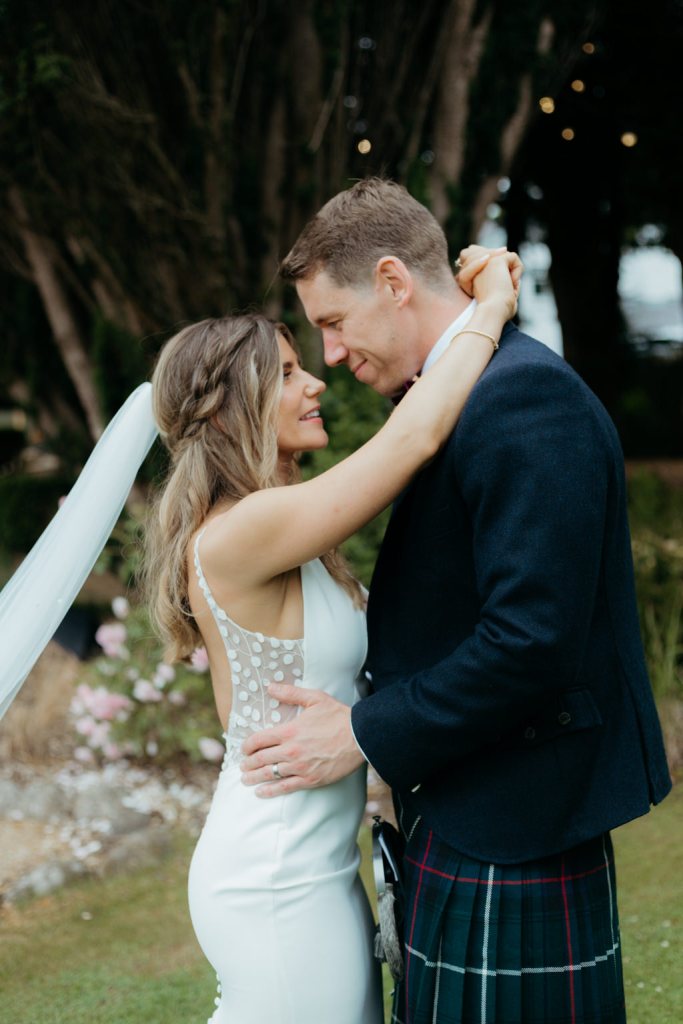 bride and groom hug and embrace in garden facing each other