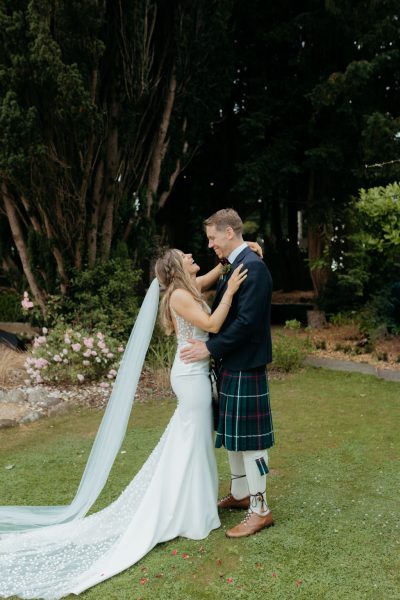 bride and groom hug and embrace in garden facing each other smiling