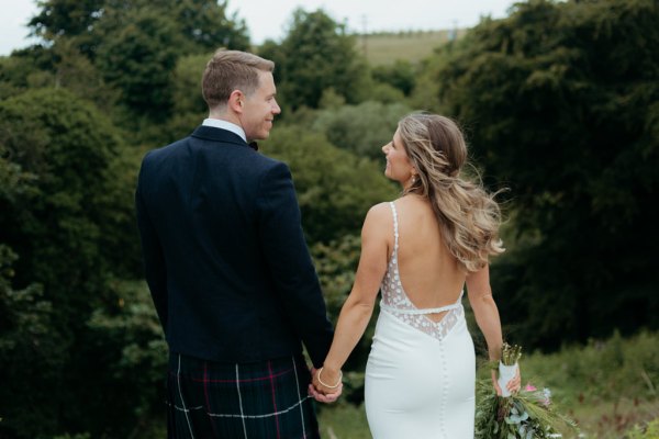 bride and groom in the garden together facing away from camera holding hands