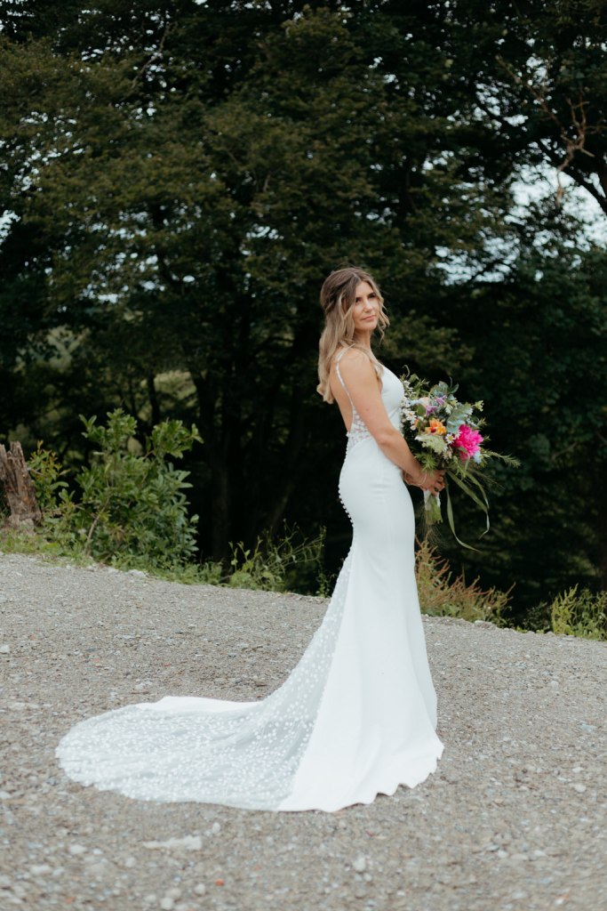 bride on her own standing in courtyard holding bouquet of flowers