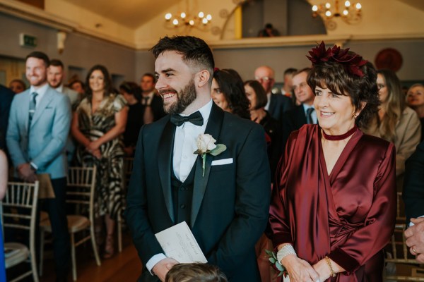 groom and mother stand together at top of alter