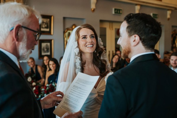 bride and groom stand at alter with celebrant she reads sermon