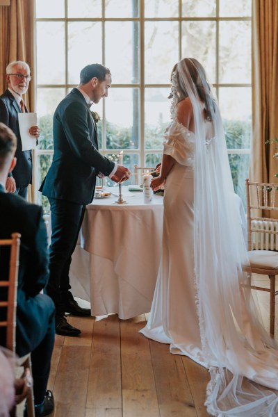 bride and groom stand at top of alter lighting candles while guests clap